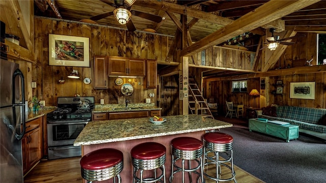 8567 Glen Rd, Rushford, NY 14777 - kitchen with ceiling fan, stainless steel range with gas cooktop, wooden walls, freestanding refrigerator, and a wooden ceiling with exposed beams