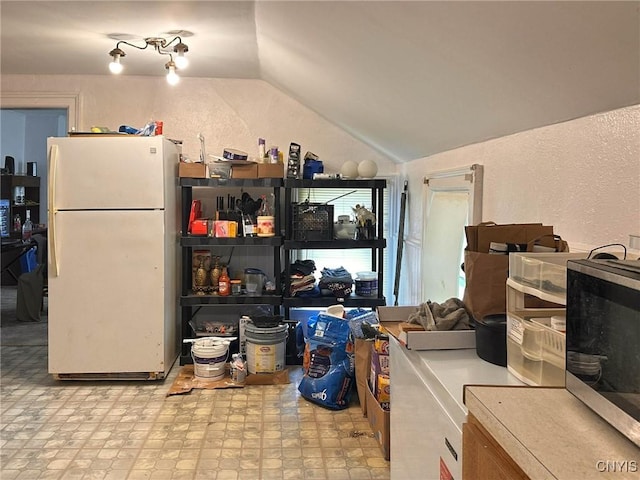 711 Stevens St, Utica, NY 13502 - kitchen featuring freestanding refrigerator, vaulted ceiling, stainless steel microwave, and a textured wall
