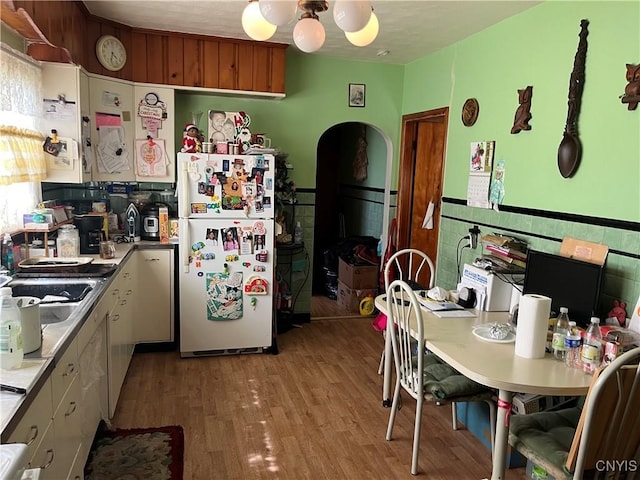 711 Stevens St, Utica, NY 13502 - kitchen featuring freestanding refrigerator, arched walkways, and light wood finished floors