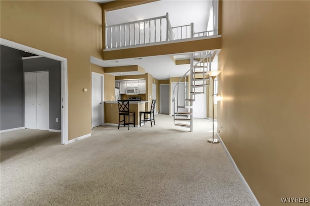 5 Keph Dr Unit 8, Amherst, NY 14228 - living room featuring a towering ceiling, light carpet, and stairs