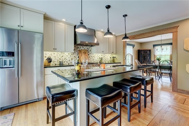 38 E Ave, Murray, NY 14470 - kitchen featuring high end fridge, wall chimney range hood, dark countertops, a kitchen breakfast bar, and ornamental molding