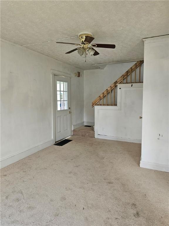 420 Schuyler Ave, Southport, NY 14904 - unfurnished living room with ceiling fan, carpet floors, a textured ceiling, and stairs
