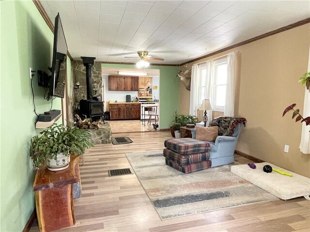 1663 Bingham Rd, Keating Town, PA 16726 - living room featuring crown molding, a wood stove, wood finished floors, and a ceiling fan
