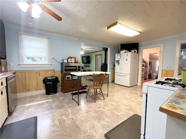 1663 Bingham Rd, Keating Town, PA 16726 - kitchen featuring stainless steel appliances, a ceiling fan, wood walls, wainscoting, and crown molding