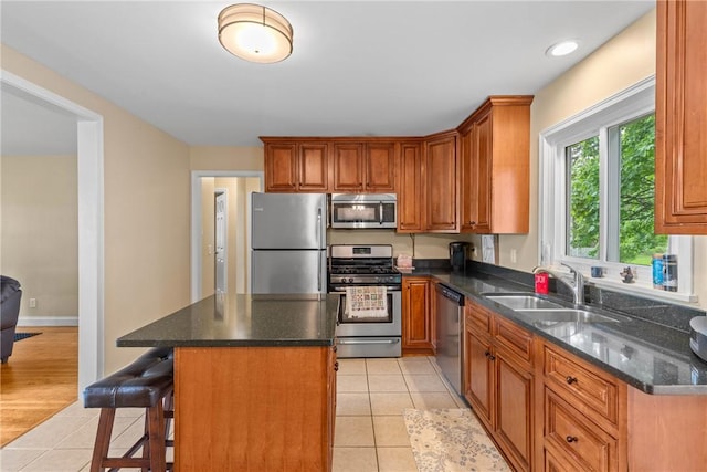 1617 Five Mile Line Rd, Penfield, NY 14526 - kitchen with appliances with stainless steel finishes, light tile patterned floors, a kitchen island, a breakfast bar, and brown cabinetry