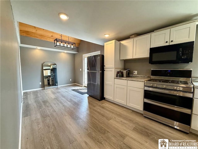 918 Crown St, Olean-City, NY 14760 - kitchen with black microwave, range with two ovens, freestanding refrigerator, arched walkways, and white cabinetry