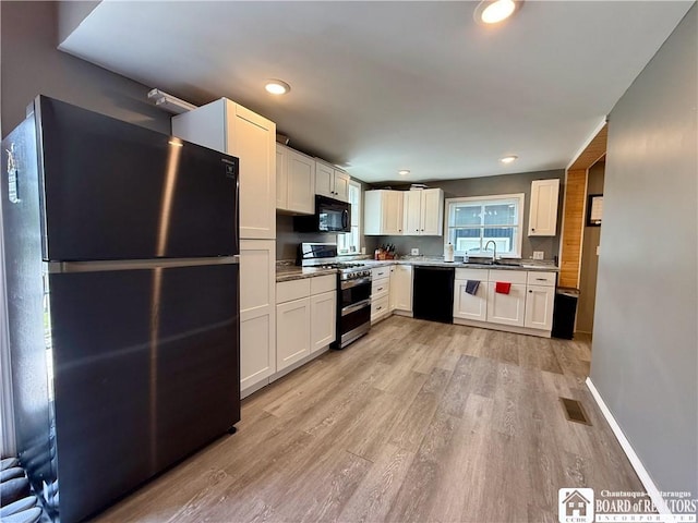 918 Crown St, Olean-City, NY 14760 - kitchen with black appliances, light wood-style floors, white cabinetry, and recessed lighting