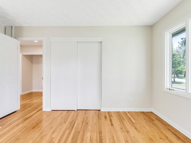 1333 Wayneport Rd, Macedon, NY 14502 - unfurnished bedroom with multiple windows, light wood-style flooring, and a closet