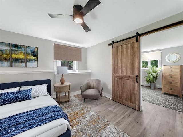1333 Wayneport Rd, Macedon, NY 14502 - bedroom featuring light wood-style flooring, a barn door, and a ceiling fan
