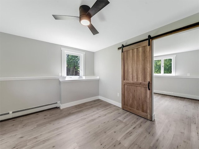 1333 Wayneport Rd, Macedon, NY 14502 - unfurnished bedroom featuring wood finished floors, a baseboard heating unit, a barn door, and ceiling fan