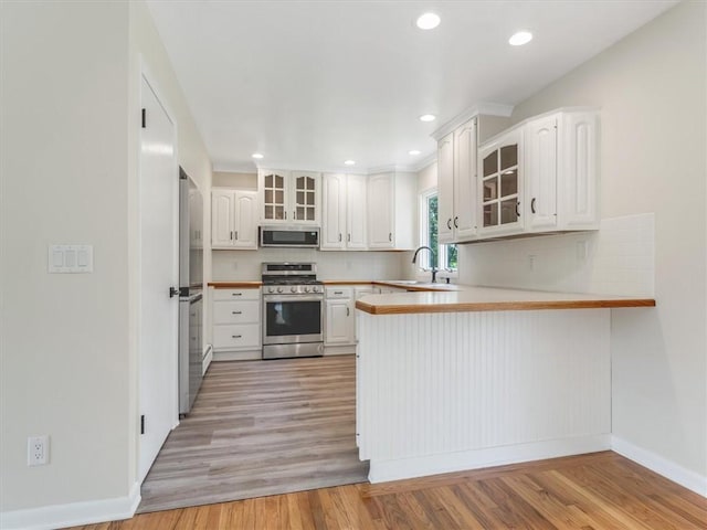 1333 Wayneport Rd, Macedon, NY 14502 - kitchen with appliances with stainless steel finishes, a peninsula, glass insert cabinets, backsplash, and recessed lighting