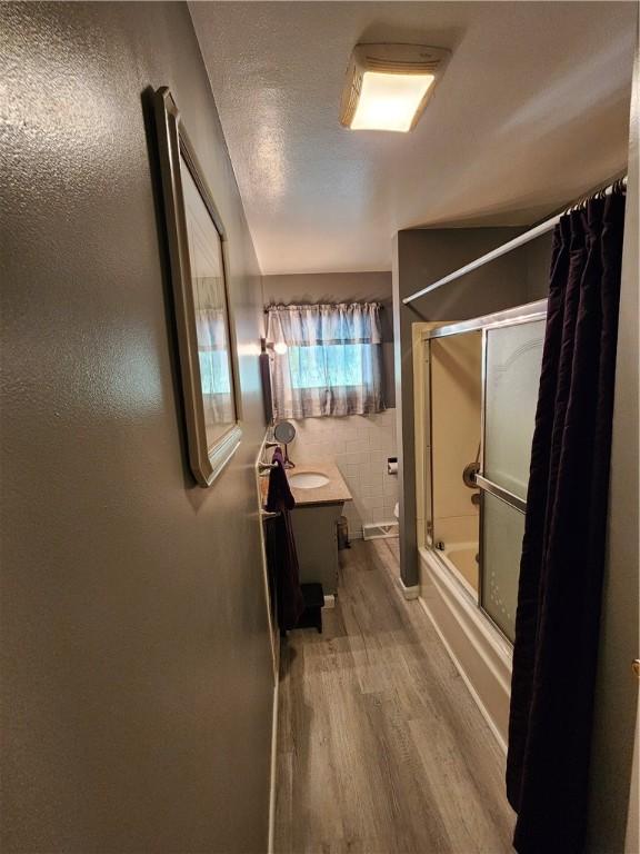 8637 State Route 415, Campbell, NY 14821 - bathroom featuring wood finished floors, vanity, and shower / bath combination with glass door