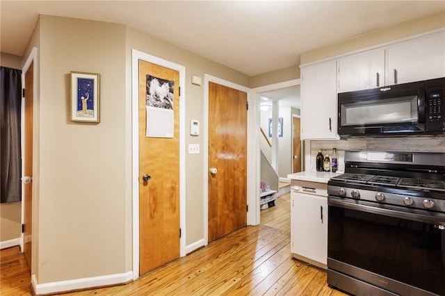 3389 Culver Rd, Irondequoit, NY 14622 - kitchen with black microwave, stainless steel gas range oven, light wood-style floors, light countertops, and white cabinets