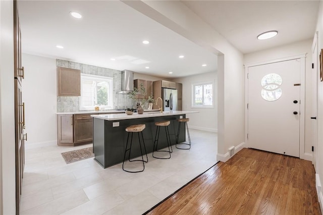 165 Culver Pkwy, Irondequoit, NY 14609 - kitchen featuring wall chimney range hood, light countertops, a kitchen breakfast bar, stainless steel fridge with ice dispenser, and tasteful backsplash