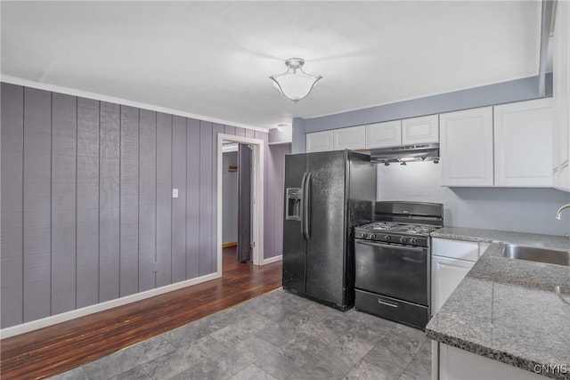 711 Mountainview Ave, Syracuse, NY 13224 - kitchen with black appliances, under cabinet range hood, white cabinets, light stone counters, and wooden walls