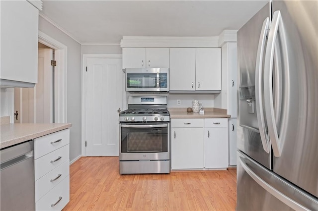225 Dorking Rd, Brighton, NY 14610 - kitchen with stainless steel appliances, light countertops, white cabinets, light wood-style floors, and ornamental molding