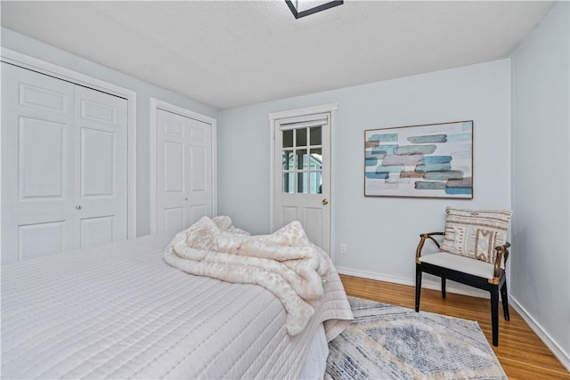 225 Dorking Rd, Brighton, NY 14610 - bedroom featuring wood finished floors, multiple closets, and a textured ceiling