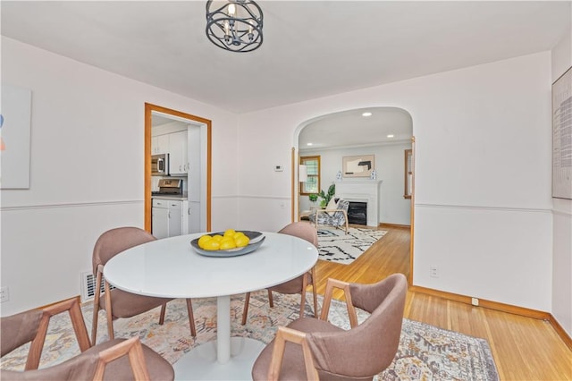 225 Dorking Rd, Brighton, NY 14610 - dining area with arched walkways, a fireplace, wood finished floors, and recessed lighting