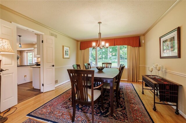 100 Broadmoor Trl, Perinton, NY 14450 - dining space with crown molding, a chandelier, light wood-type flooring, and a textured ceiling