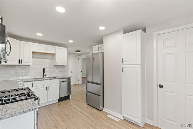 331 Darlington Rd, Syracuse, NY 13208 - kitchen with appliances with stainless steel finishes, white cabinets, light wood-type flooring, decorative backsplash, and recessed lighting