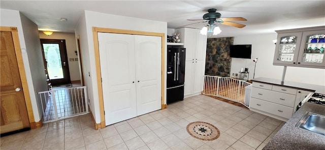 527 Harper Rd, Harpersfield, NY 13786 - kitchen with black fridge with ice dispenser, a ceiling fan, light tile patterned flooring, dark countertops, and white cabinetry