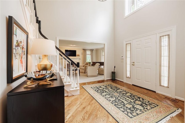 7974 Oak Brook Cir, Pittsford, NY 14534 - entryway featuring stairway, a towering ceiling, and wood finished floors