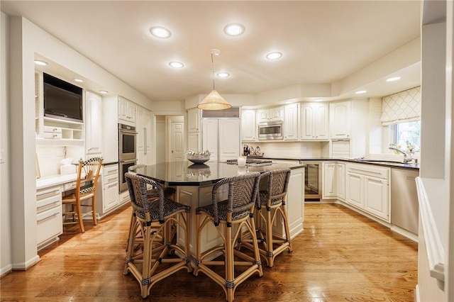 7974 Oak Brook Cir, Pittsford, NY 14534 - kitchen featuring built in appliances, recessed lighting, dark countertops, a breakfast bar, and a center island