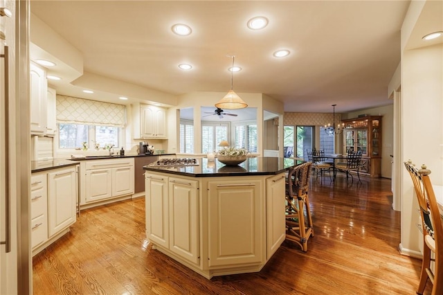7974 Oak Brook Cir, Pittsford, NY 14534 - kitchen featuring dark countertops, a kitchen island, light wood-style flooring, recessed lighting, and a chandelier