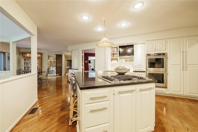 7974 Oak Brook Cir, Pittsford, NY 14534 - kitchen featuring stainless steel appliances, white cabinets, light wood-type flooring, decorative light fixtures, and a center island