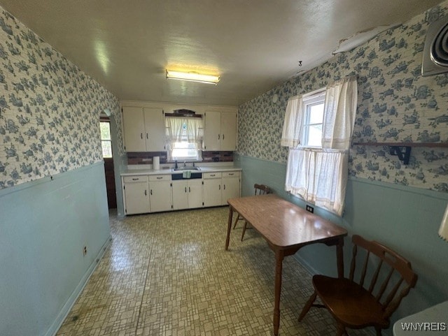 715 83rd St, Niagara Falls, NY 14304 - kitchen with wallpapered walls, wainscoting, white cabinets, light countertops, and light floors