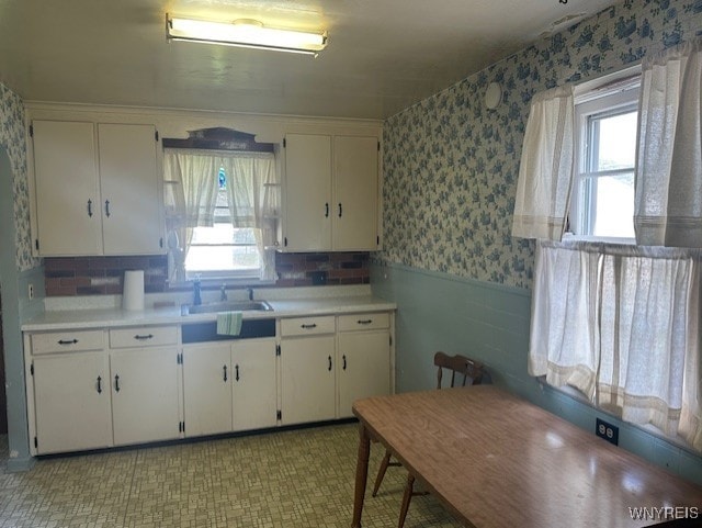 715 83rd St, Niagara Falls, NY 14304 - kitchen with wallpapered walls, a wainscoted wall, white cabinetry, and light countertops
