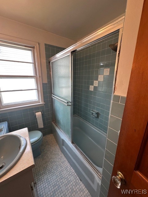 715 83rd St, Niagara Falls, NY 14304 - full bath featuring tile walls, tile patterned flooring, vanity, shower / bath combination with glass door, and wainscoting