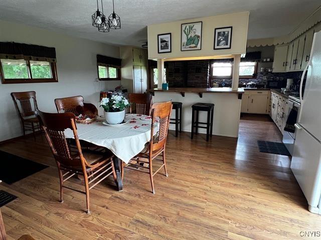 298 Maple Ridge Rd, Dekalb, NY 13681 - dining area featuring plenty of natural light, light wood-type flooring, a chandelier, and a textured ceiling