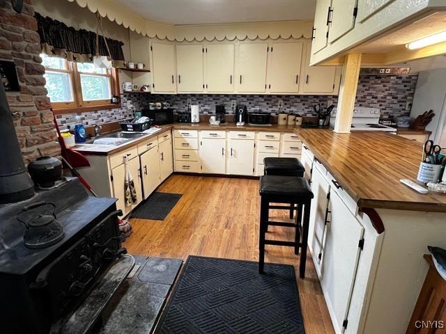 298 Maple Ridge Rd, Dekalb, NY 13681 - kitchen featuring light wood-style flooring, tasteful backsplash, stove, wood counters, and a peninsula