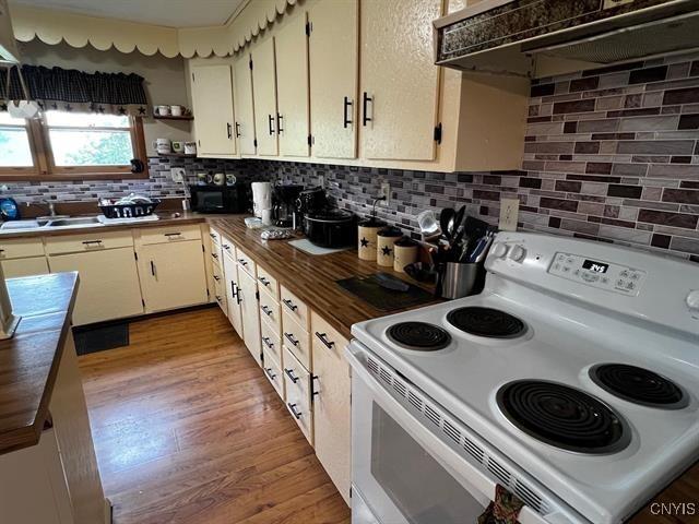 298 Maple Ridge Rd, Dekalb, NY 13681 - kitchen featuring white electric range, under cabinet range hood, black microwave, butcher block countertops, and tasteful backsplash