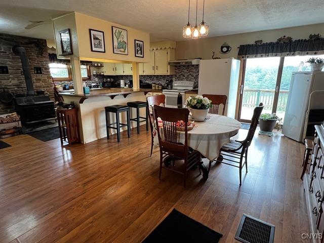 298 Maple Ridge Rd, Dekalb, NY 13681 - dining area featuring a wood stove, dark wood-style flooring, and a textured ceiling