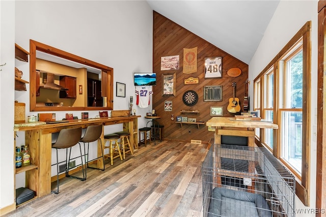 28 Woodstock Rd, Concord, NY 14069 - bar featuring wooden walls, high vaulted ceiling, wall chimney exhaust hood, wood finished floors, and an accent wall