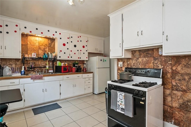 128 Clifford Ave, Rochester, NY 14621 - kitchen featuring gas range oven, freestanding refrigerator, backsplash, white cabinets, and light tile patterned floors