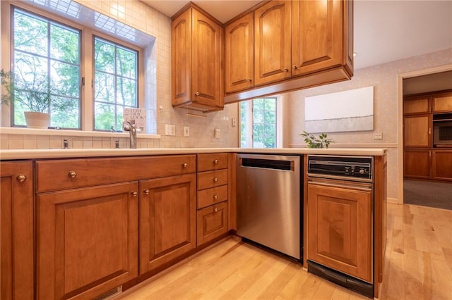 115 Crandon Way, Brighton, NY 14618 - kitchen with stainless steel dishwasher, brown cabinetry, light wood-type flooring, and light countertops