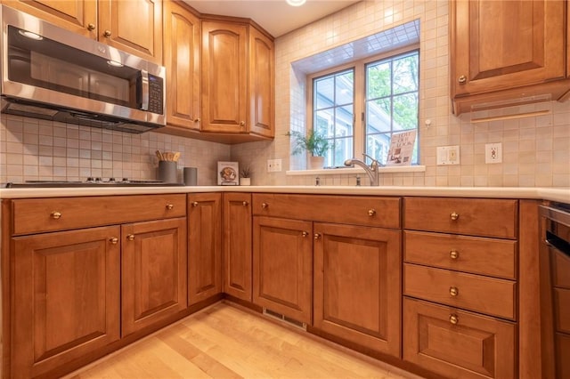 115 Crandon Way, Brighton, NY 14618 - kitchen featuring stainless steel microwave, brown cabinetry, light wood-style floors, and light countertops