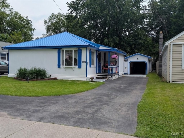 2008 Main St, Vienna, NY 13157 - view of front of house with an outdoor structure, asphalt driveway, a detached garage, a front yard, and a metal roof