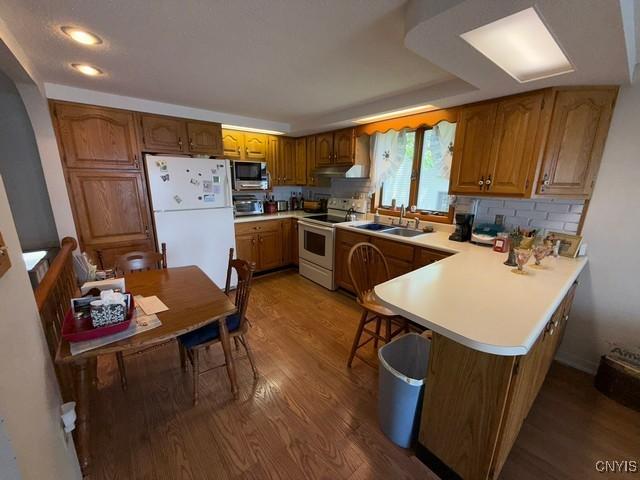 27217 Three Mile Point Rd, Lyme, NY 13622 - kitchen with white appliances, wood finished floors, a peninsula, light countertops, and recessed lighting
