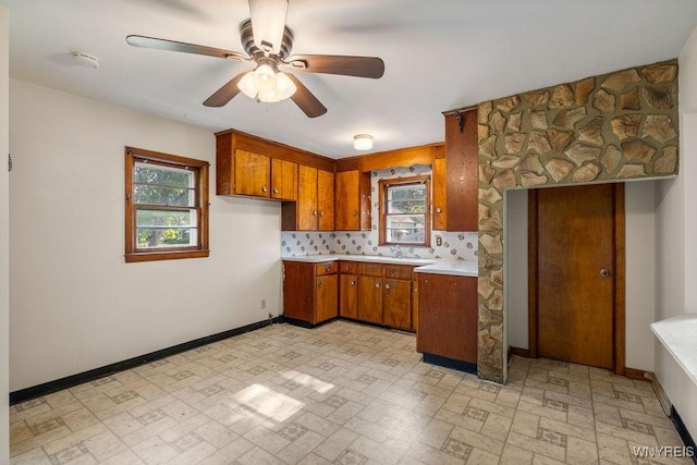 446 77th St, Niagara Falls, NY 14304 - kitchen with brown cabinetry, a ceiling fan, light countertops, brick patterned floors, and backsplash