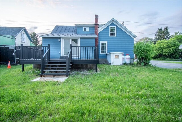 8430 Willow St, Le Ray, NY 13637 - back of property featuring a standing seam roof, a wooden deck, a metal roof, a chimney, and a lawn