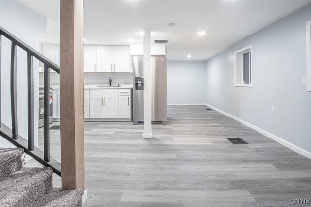 8430 Willow St, Le Ray, NY 13637 - below grade area featuring stainless steel fridge, stairway, light wood-type flooring, and recessed lighting