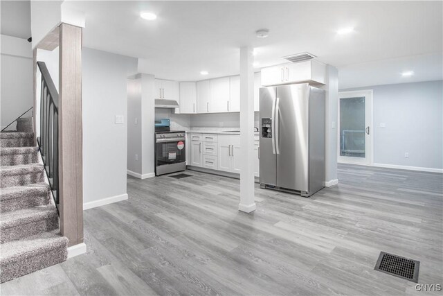 8430 Willow St, Le Ray, NY 13637 - kitchen with appliances with stainless steel finishes, under cabinet range hood, white cabinets, light wood-style flooring, and light countertops