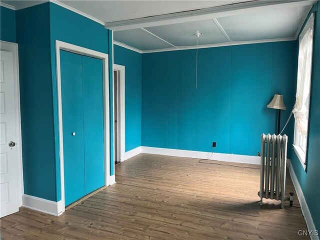 19 Genesee Ct Unit 19, Utica, NY 13502 - unfurnished bedroom with radiator, dark wood finished floors, crown molding, and a closet