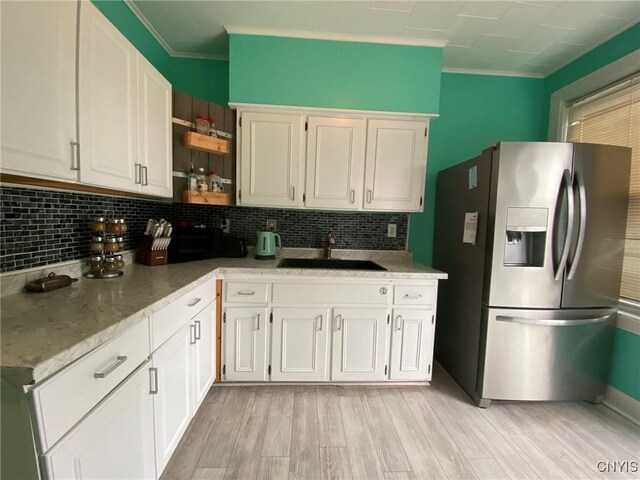 19 Genesee Ct Unit 19, Utica, NY 13502 - kitchen with stainless steel fridge, crown molding, decorative backsplash, white cabinets, and light wood-style floors