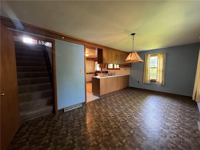 28 Mckune Ave, Foster-Town, PA 16701 - kitchen with a peninsula, open floor plan, hanging light fixtures, light countertops, and brown cabinets