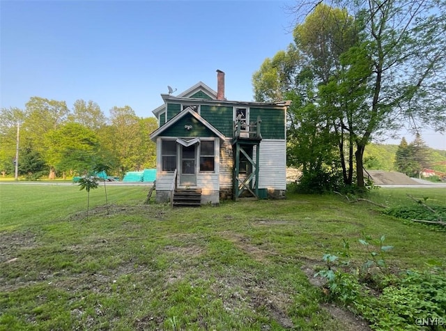 129 N Main St, Manheim, NY 13329 - back of house featuring a lawn, entry steps, a chimney, and a sunroom